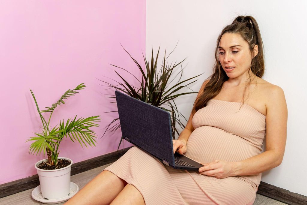 Pregnant woman googles pregnancy rhinitis on laptop.