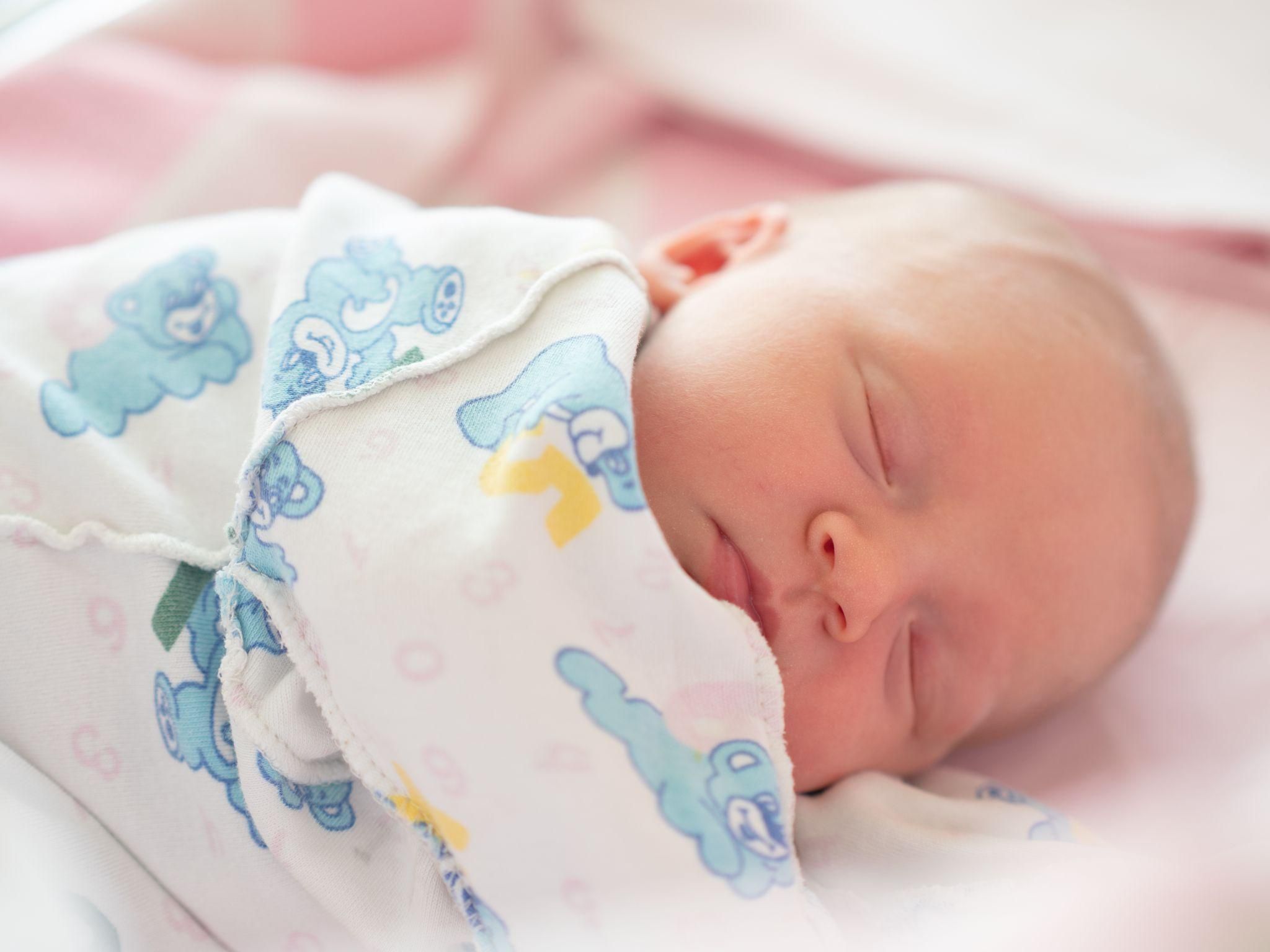 Newborn baby sleeping with a feeding bottle next to them.