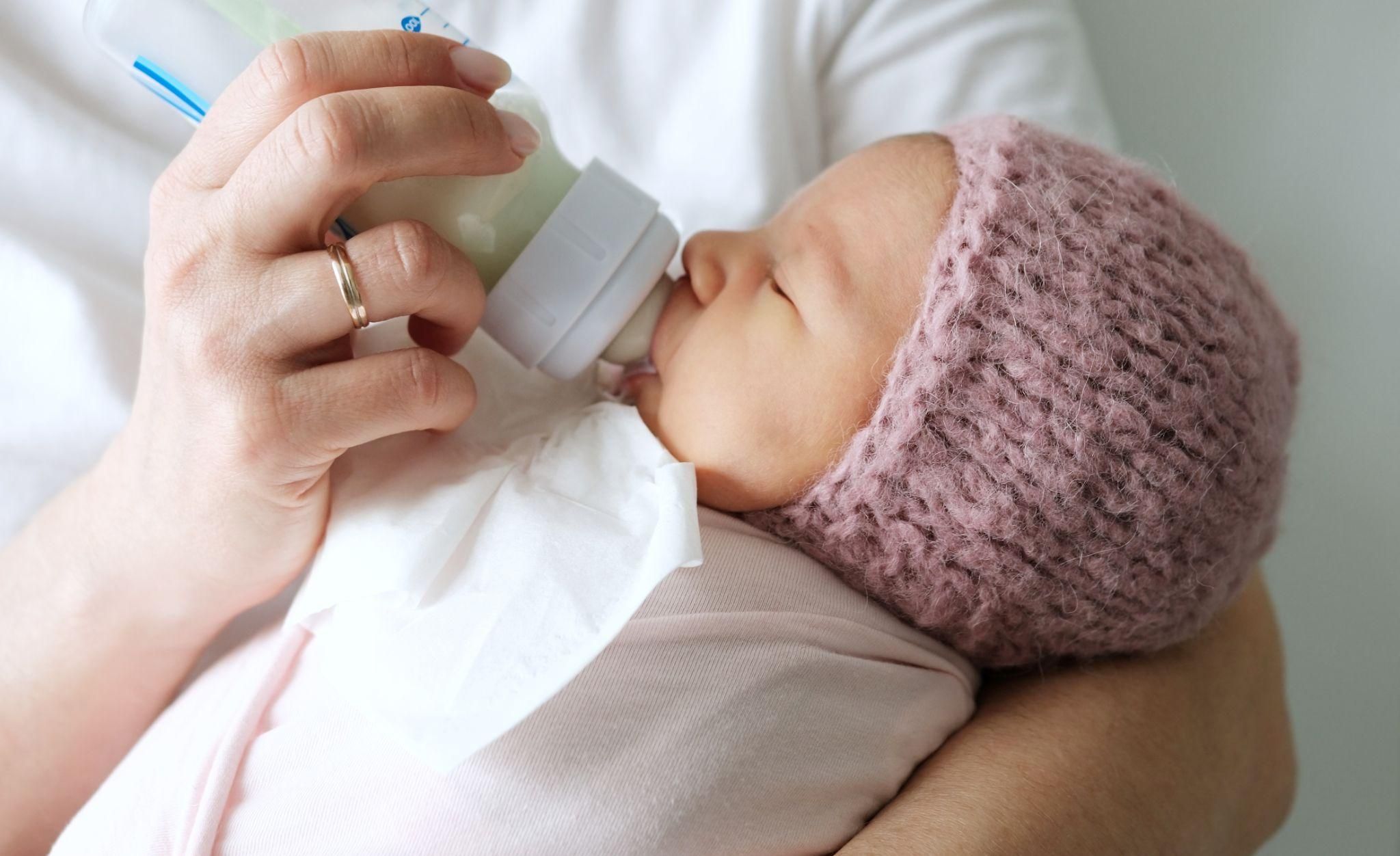 Woman bottlefeeds her newborn with expressed breast milk and colostrum.