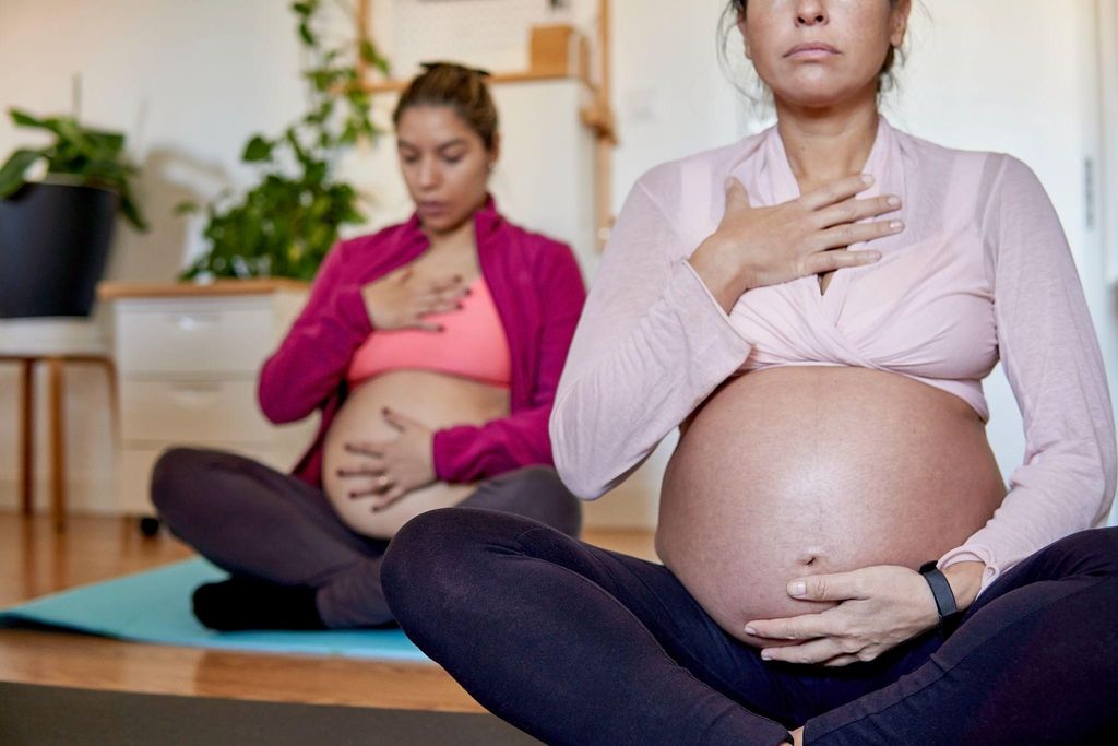 A serene pregnant woman focusing on antenatal breathing during yoga.