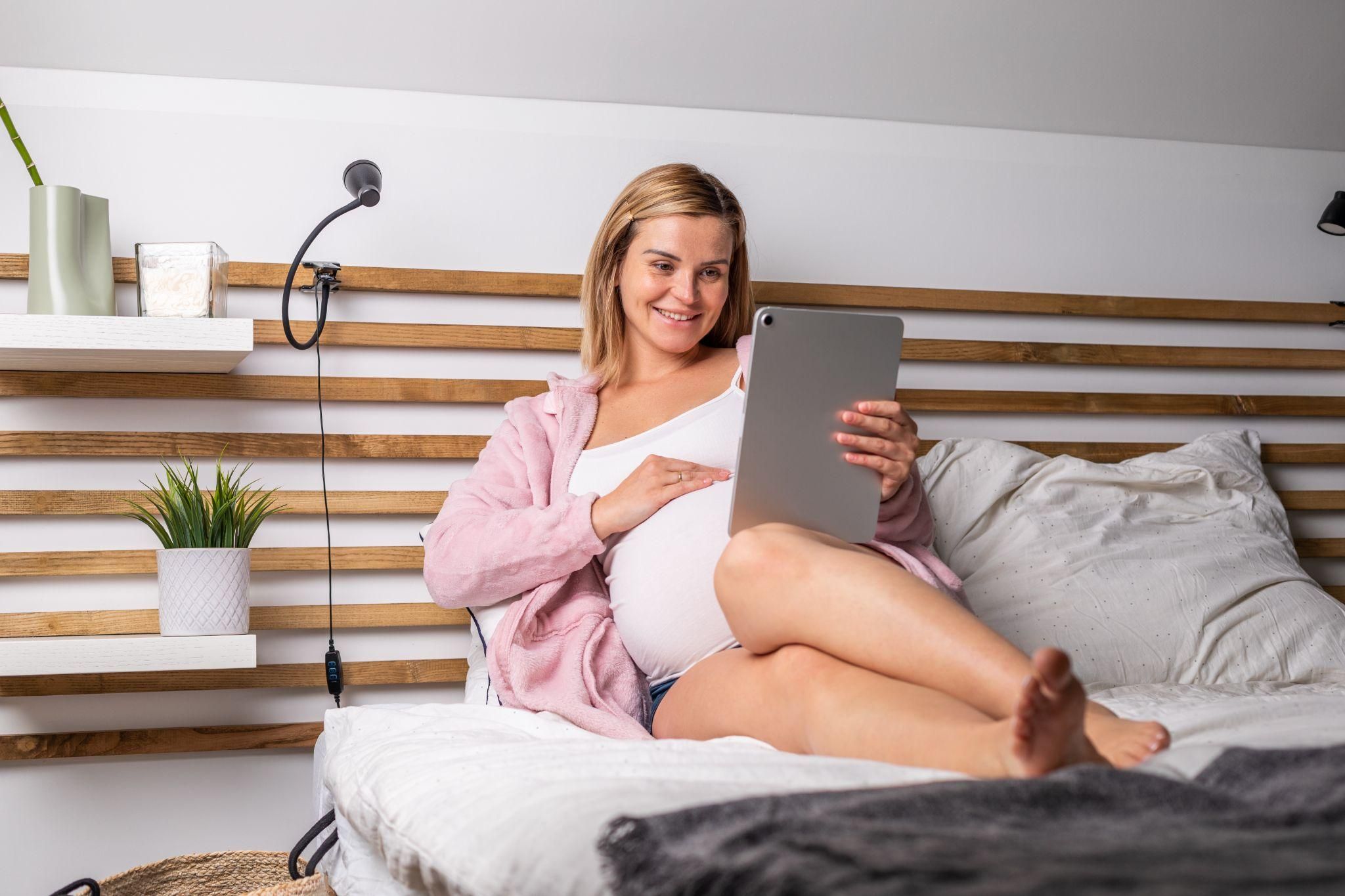 A pregnant woman relaxing with Netflix during early labour, staying calm and entertained.