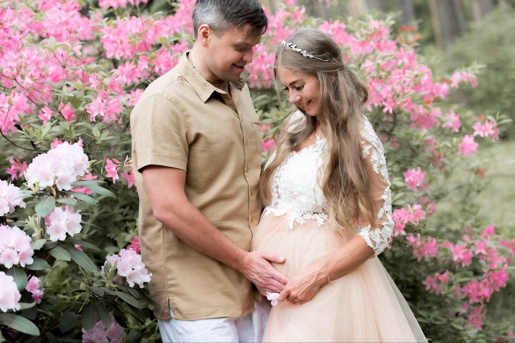 Pregnant woman in an outdoor meadow, embracing her baby bump with joy.