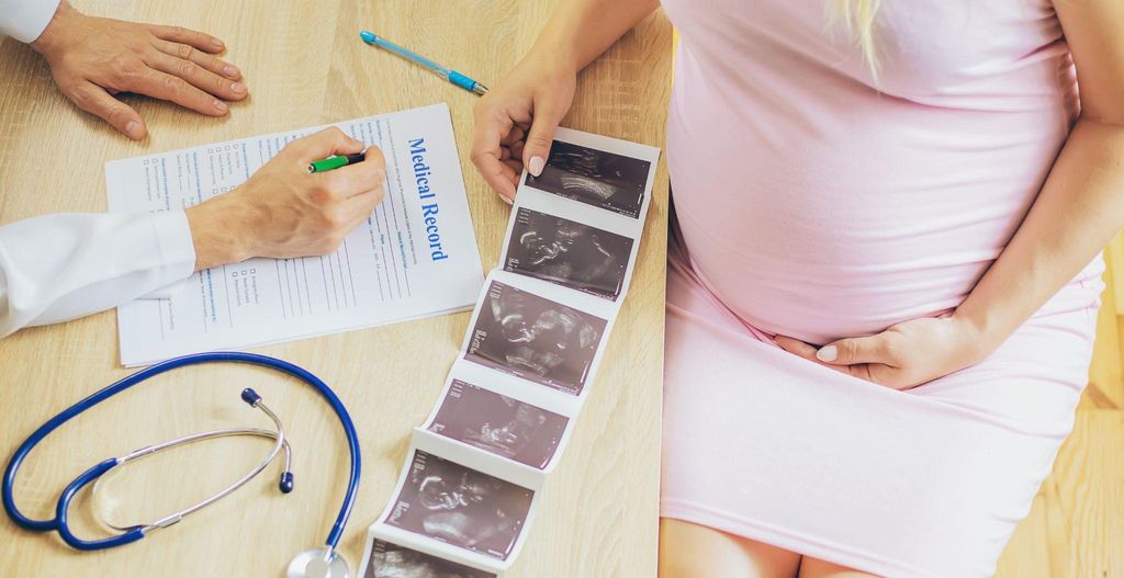 A pregnant woman reviewing her antenatal testing schedule with a healthcare provider.