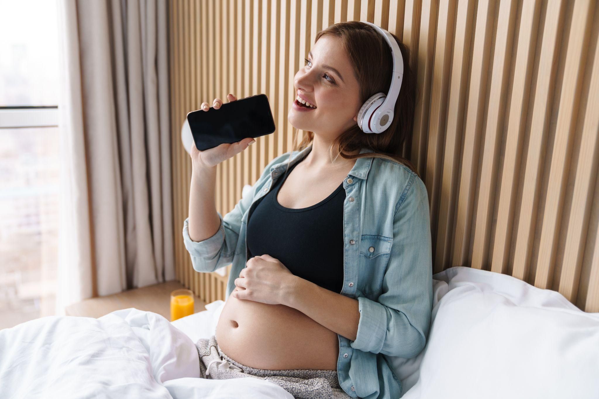 Pregnant woman reducing phone radiation exposure using speakerphone.