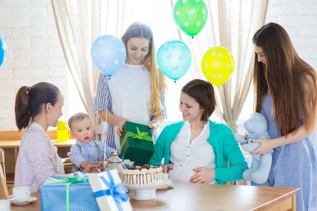 A group of friends enjoying baby shower games with colourful printouts and props.