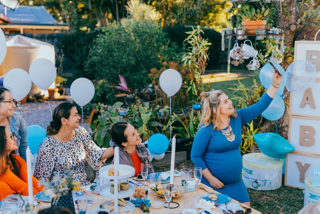 A group of friends enjoying mess-free baby shower games around a table.