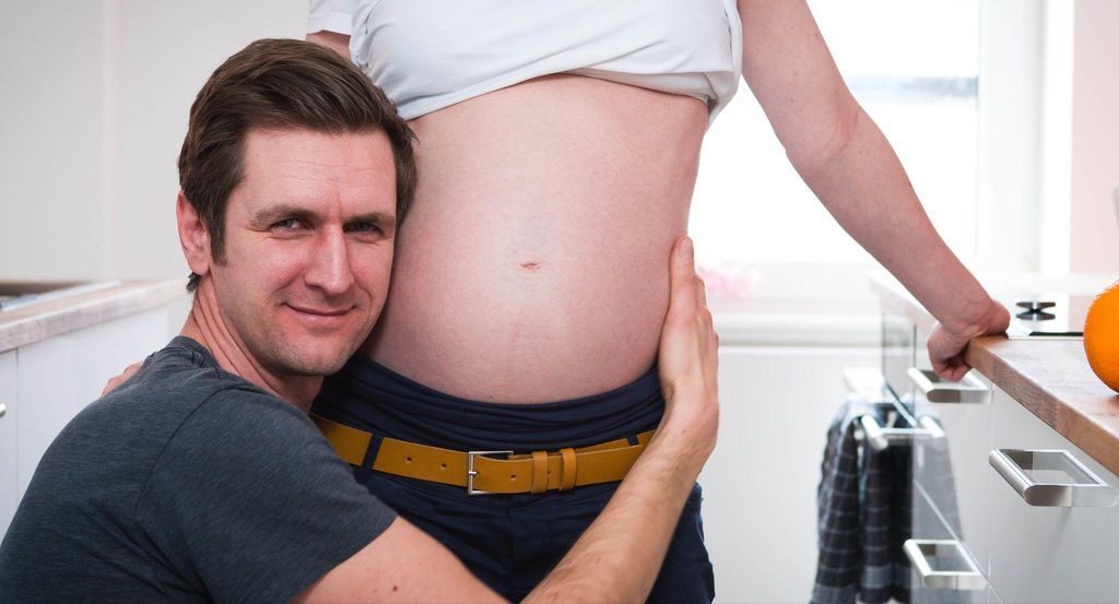 A husband and wife bonding during pregnancy, showing support and care.