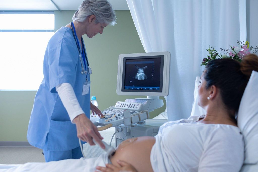 Pregnant woman has ultrasound scan with obstetrician during antenatal appointment.