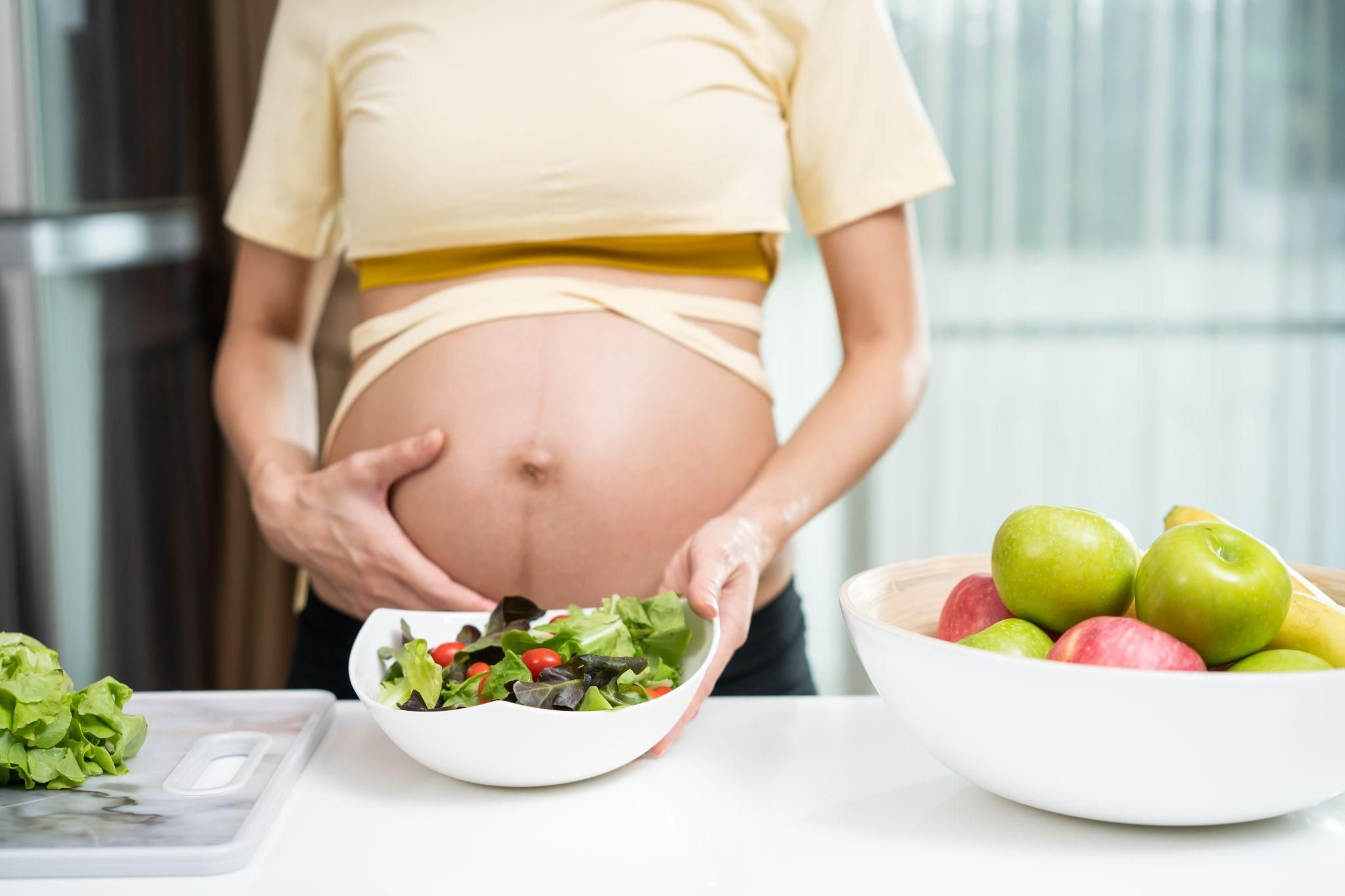 Pregnant woman enjoys colourful salad as part of her antenatal diet.