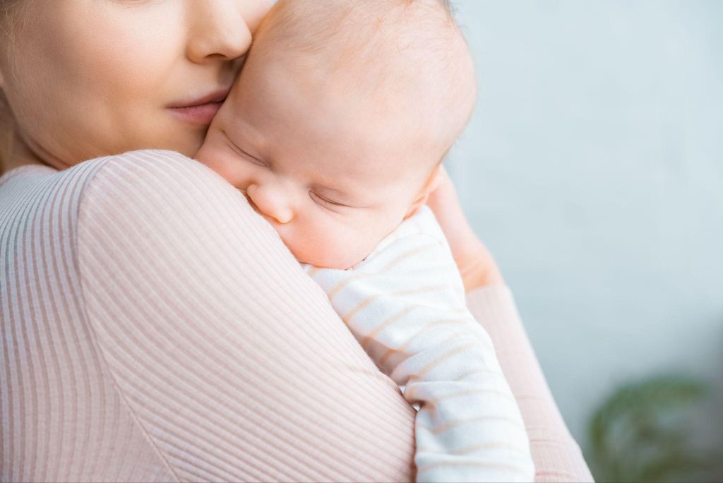 A mother cradling her newborn, representing the nurturing environment of the newborn bubble.