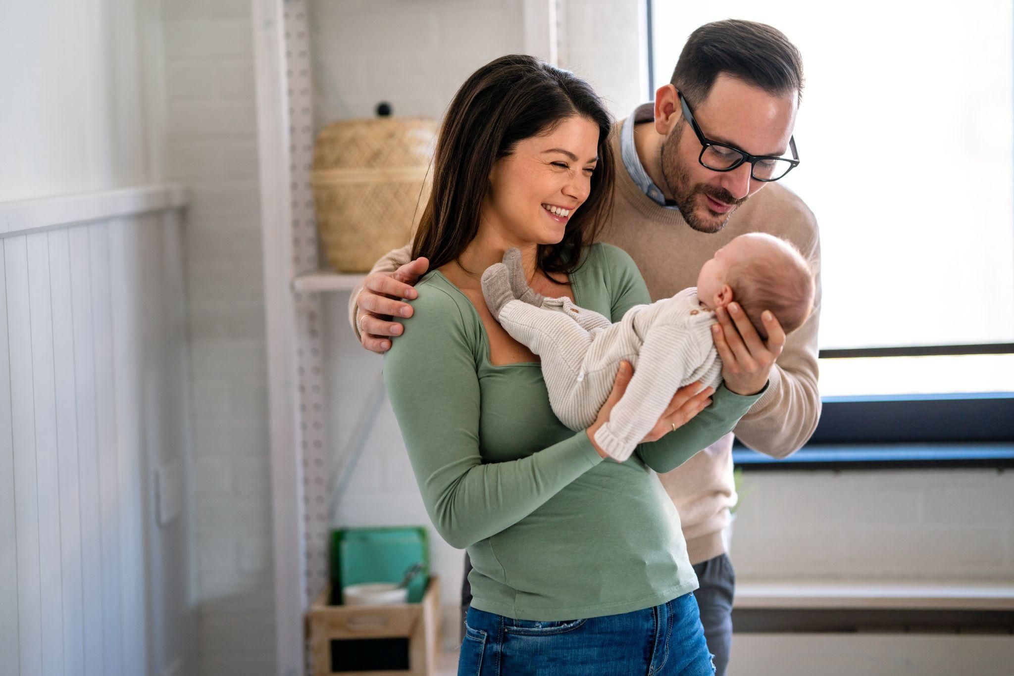 A supportive father holding his newborn baby while comforting his partner during the postpartum period.