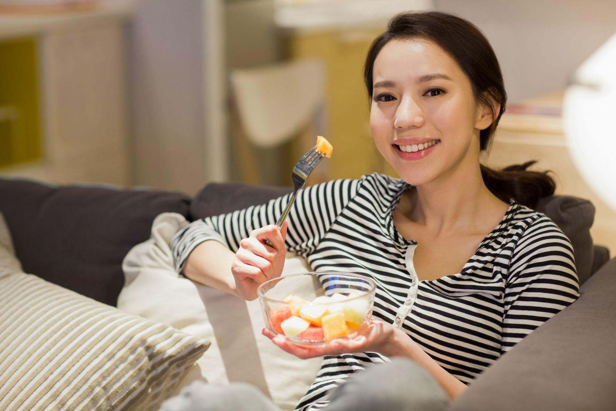 Pregnant woman enjoys a fruit salad for dessert as part of her antenatal diet.