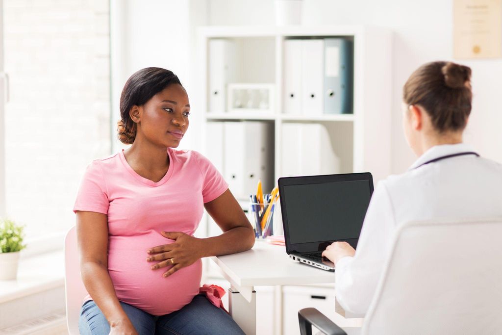 A pregnant woman discussing genetic testing options with her doctor during an antenatal appointment.