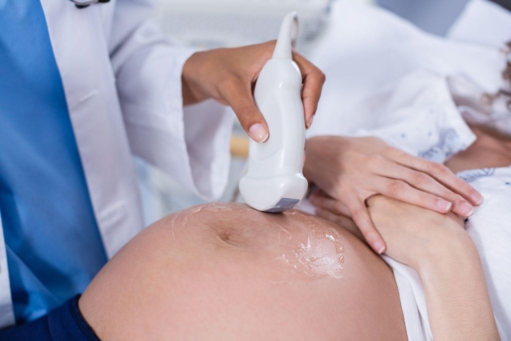 A healthcare professional conducting an ultrasound scan on a pregnant woman.