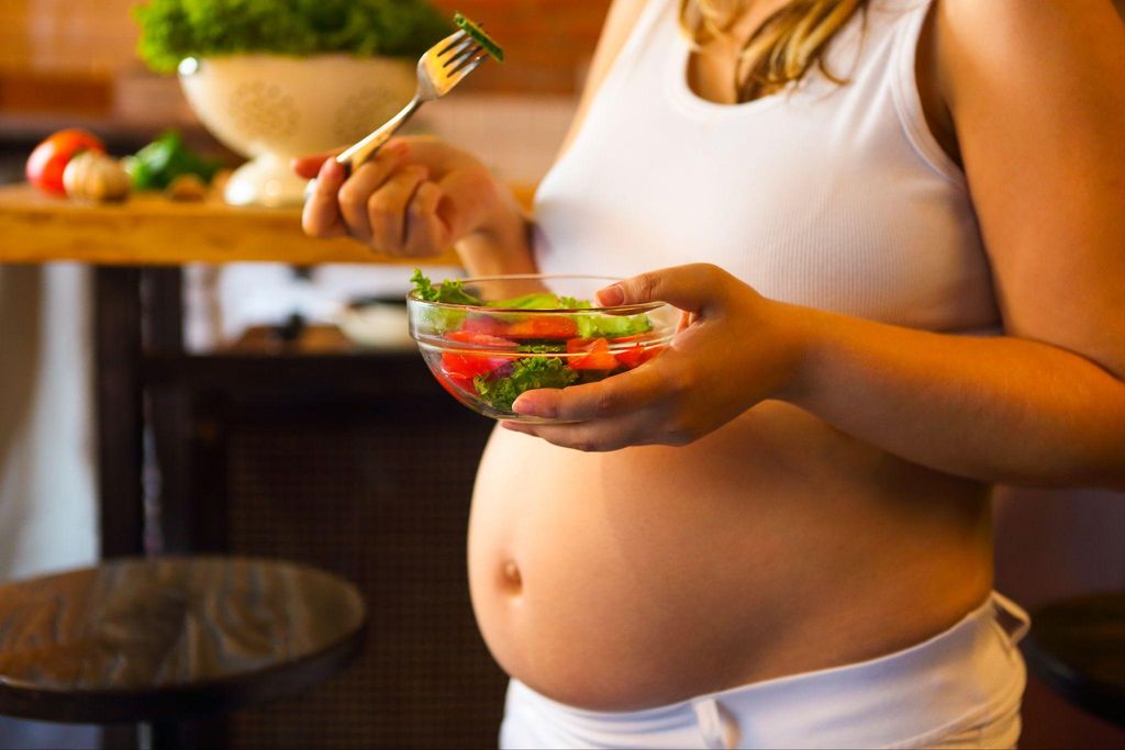 A pregnant woman eats a salad as part of her antenatal diet.