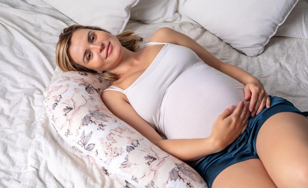 A pregnant woman sitting comfortably with her hands on her belly, symbolising care and comfort during pregnancy.