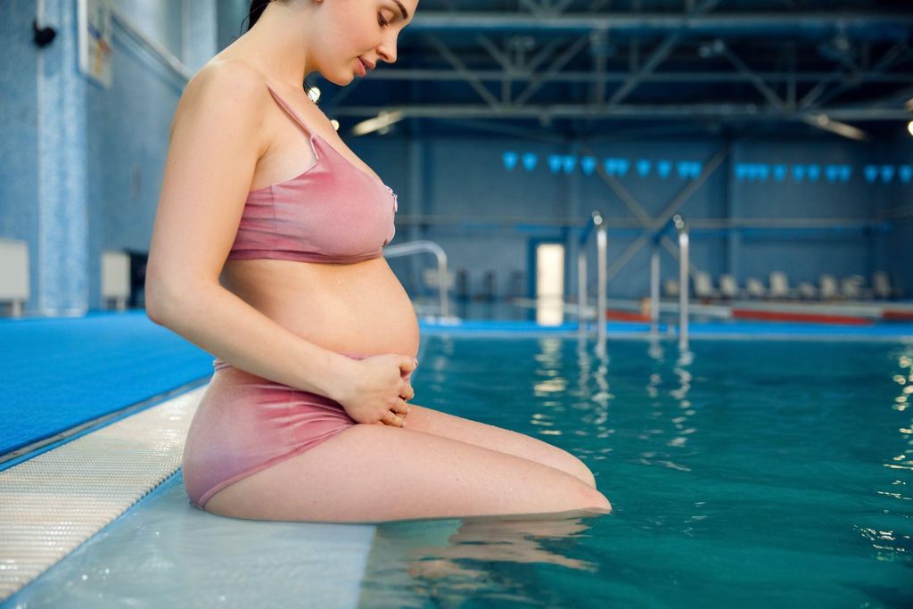 Pregnant woman inspecting her tummy for stretch marks.