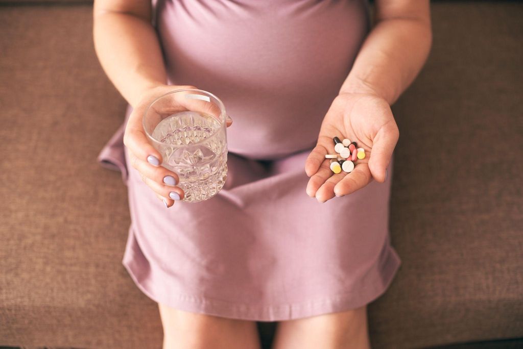 Pregnant woman takes antenatal vitamins with water.