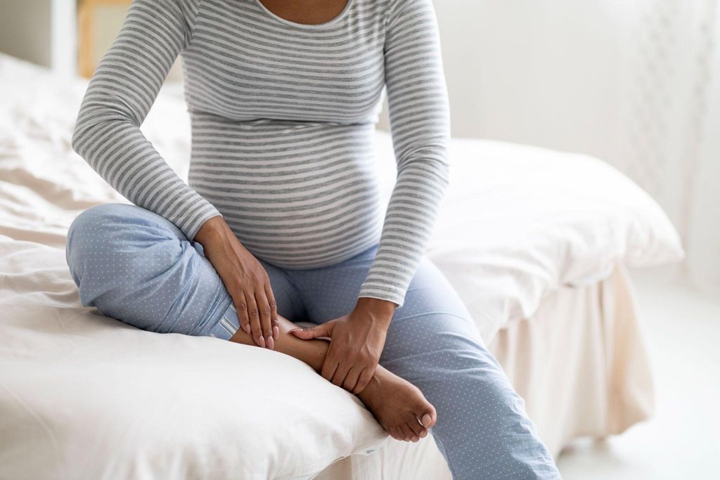 Pregnant woman sitting with a pregnancy pillow, adjusting her posture to relieve rib discomfort.