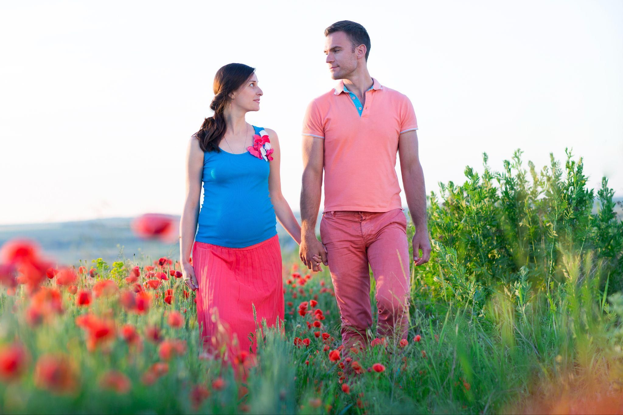 A smiling pregnant couple embracing and supporting each other.