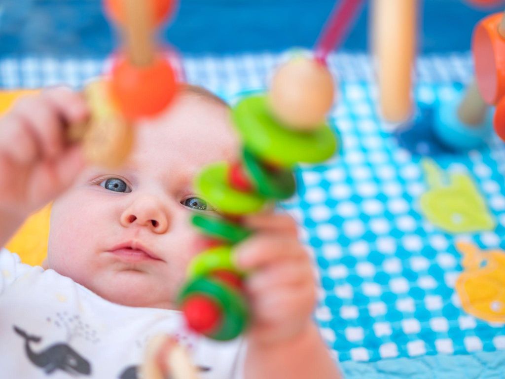 Various baby toys, including sensory, musical, and developmental options, displayed on a nursery shelf.