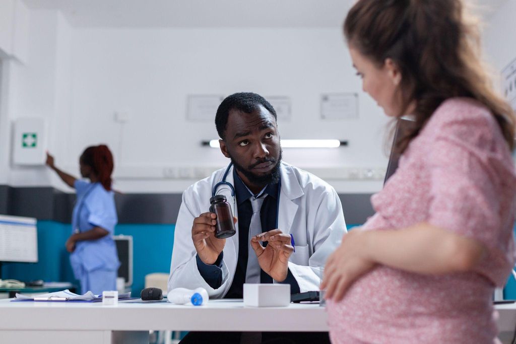 Doctor discusses the importance of prenatal vitamins with a pregnant woman during an antenatal care appointment.