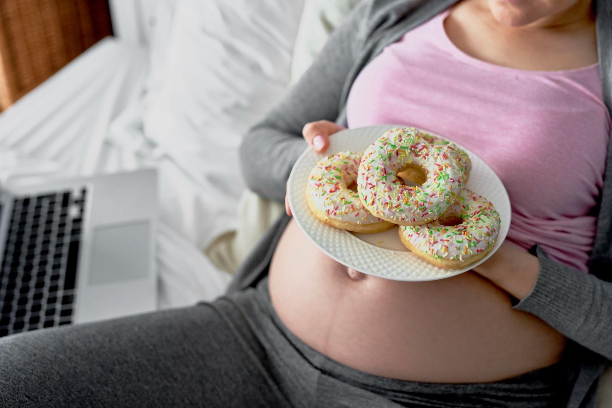 Pregnant woman with plate of donuts.