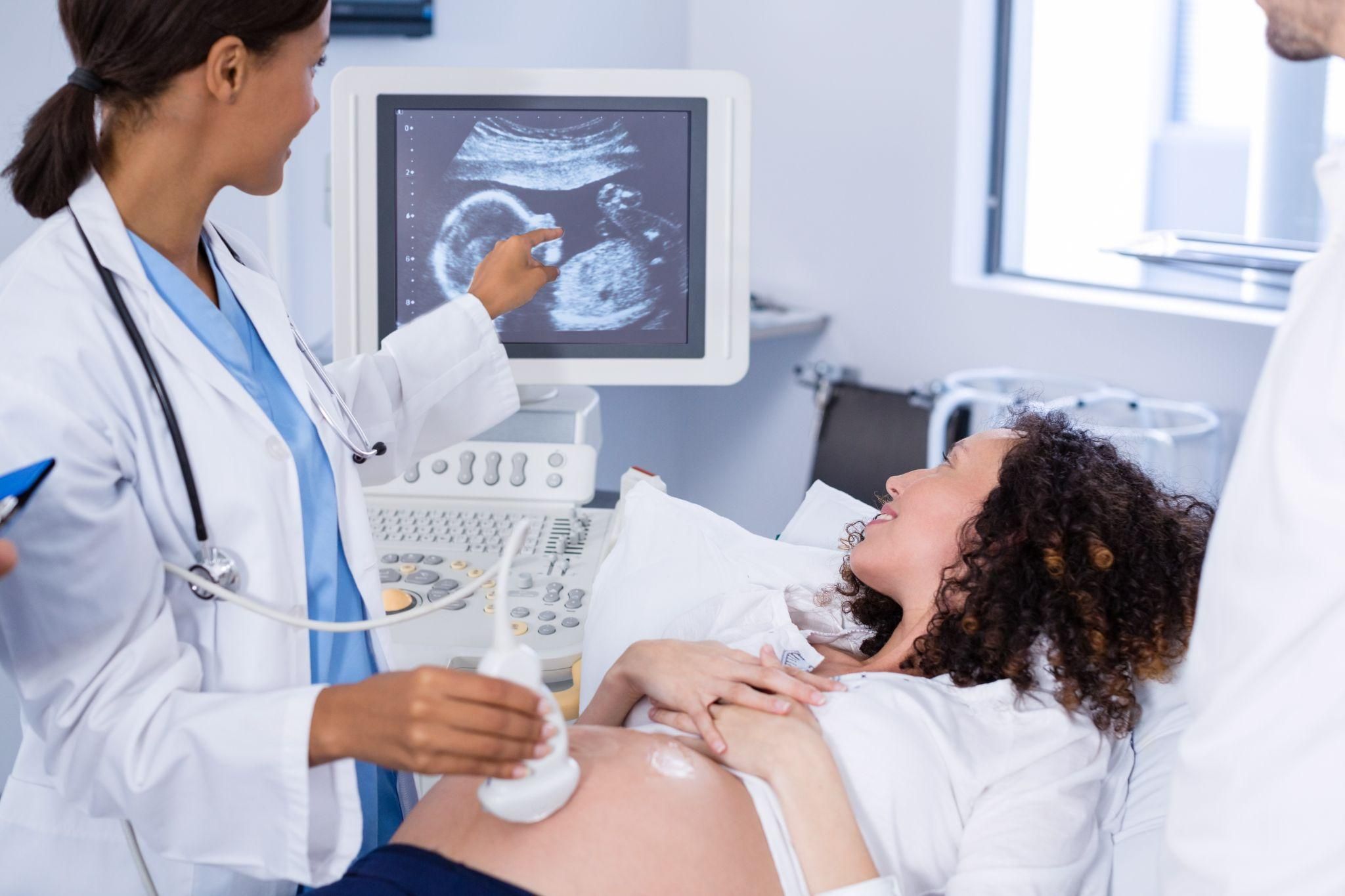 Pregnant woman has ultrasound scan with obstetrician during antenatal appointment.