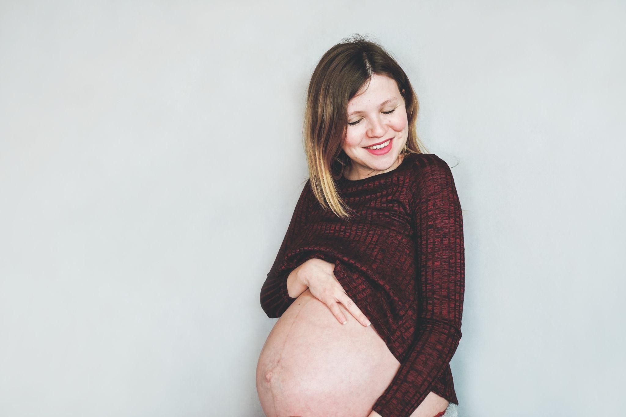 Pregnant woman showcasing her baby bump while focusing on antenatal care and wellness.