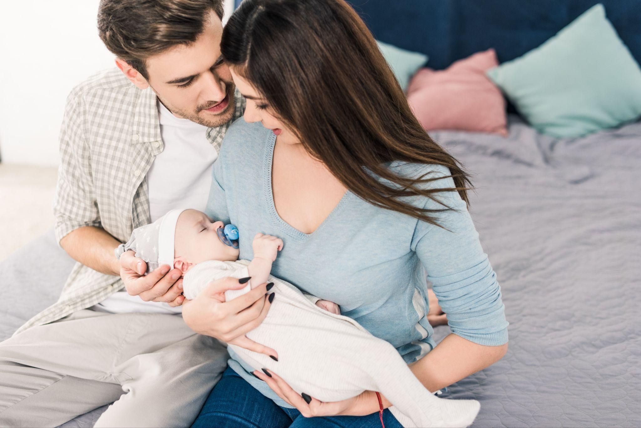 A couple bonding with their newborn in a cosy home setting.