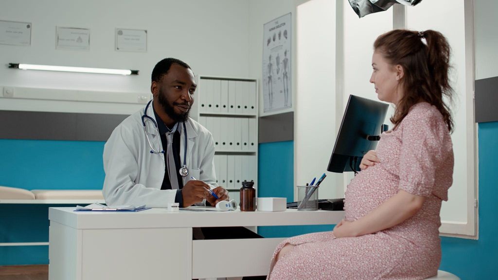 A pregnant woman discusses her symptoms with a healthcare provider during an antenatal appointment.