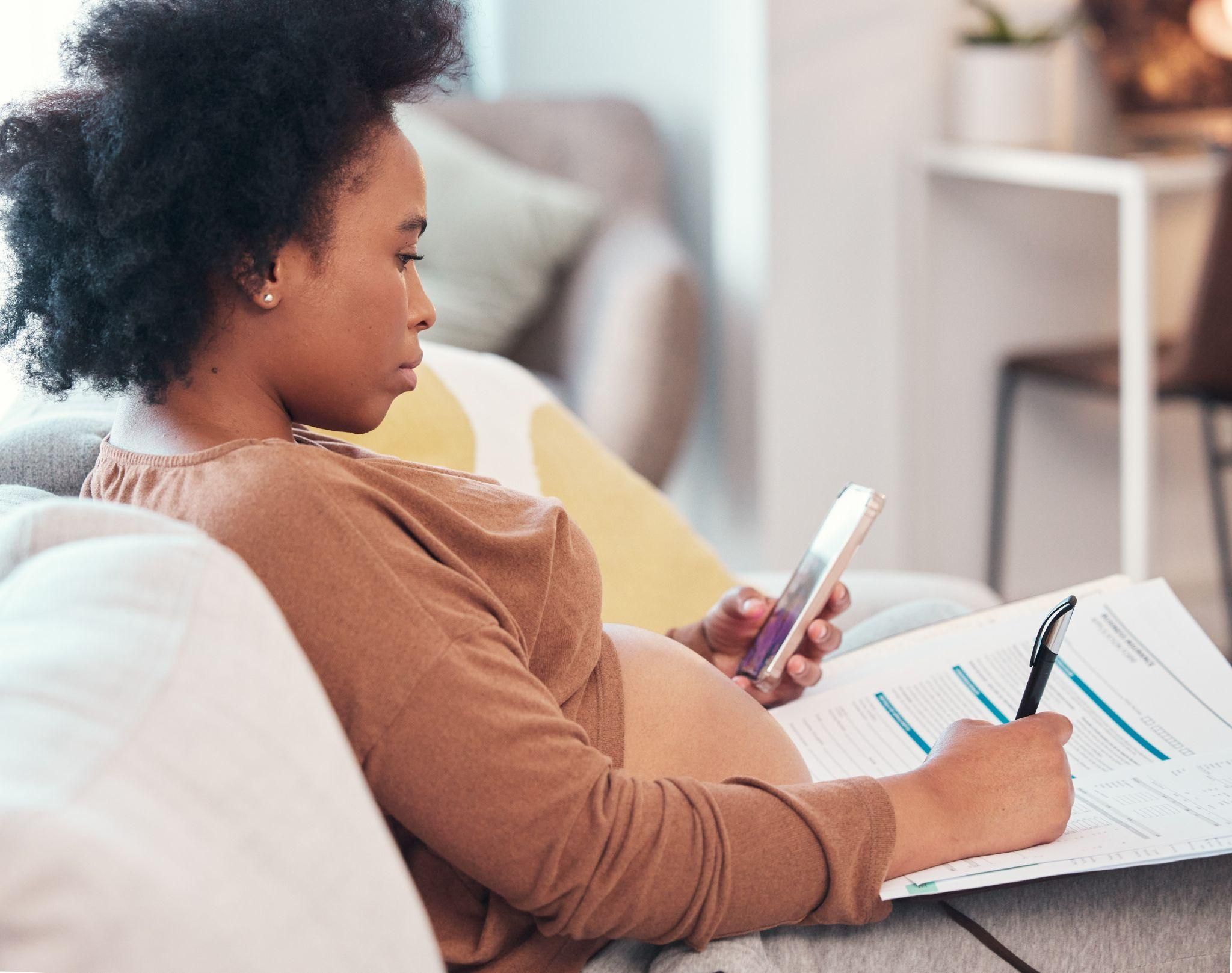 Pregnant woman writing a birth plan at a desk.