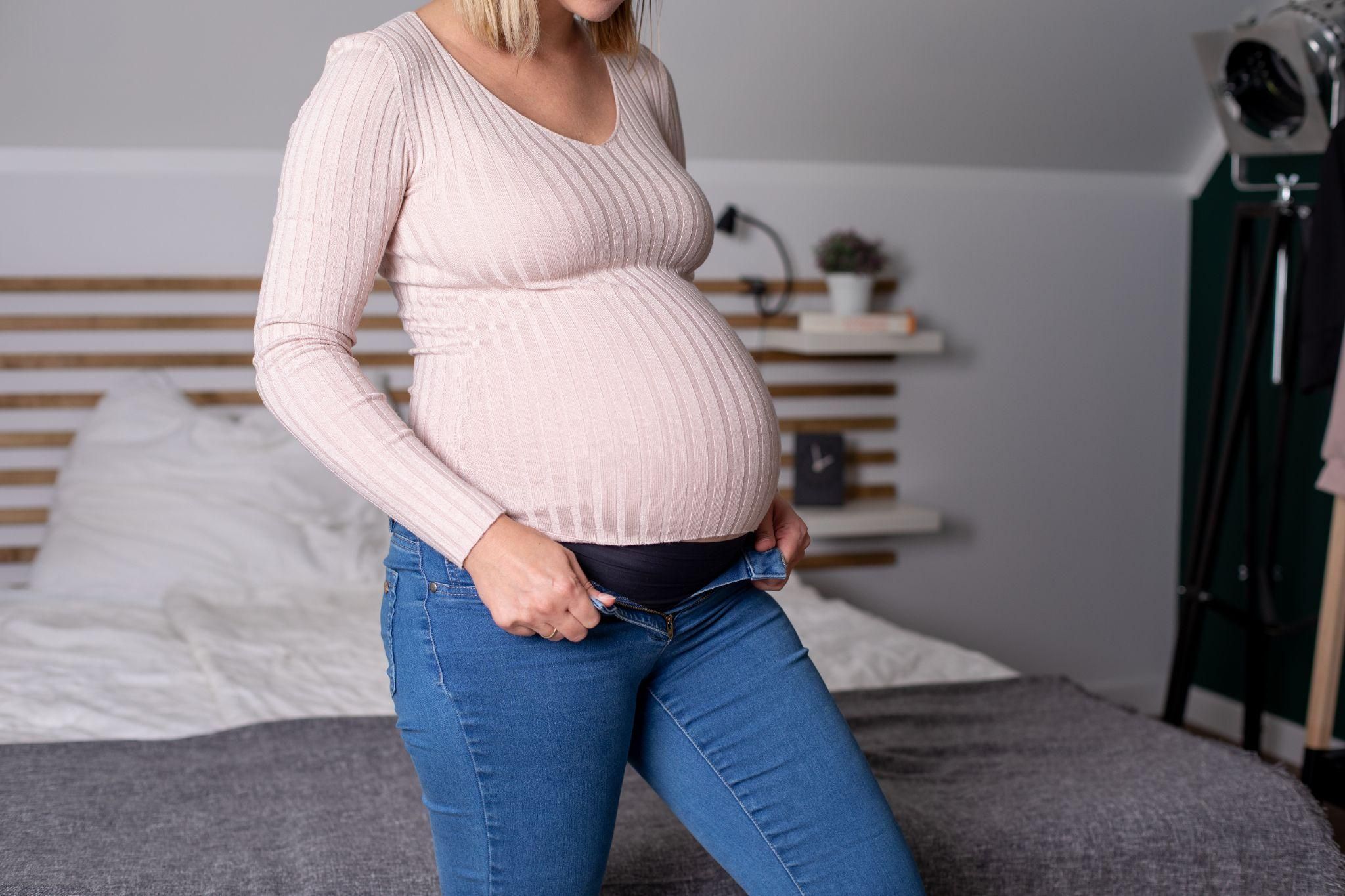 Pregnant woman can no longer fit into skinny jeans.