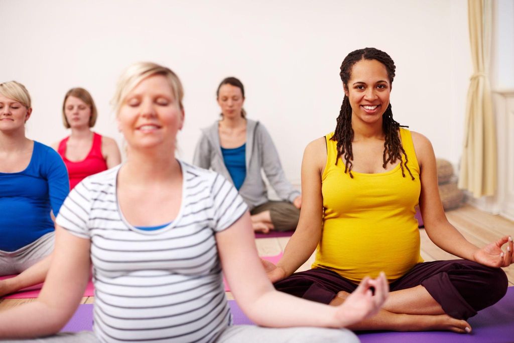 A pregnant woman sitting upright with proper antenatal posture and a supportive cushion.