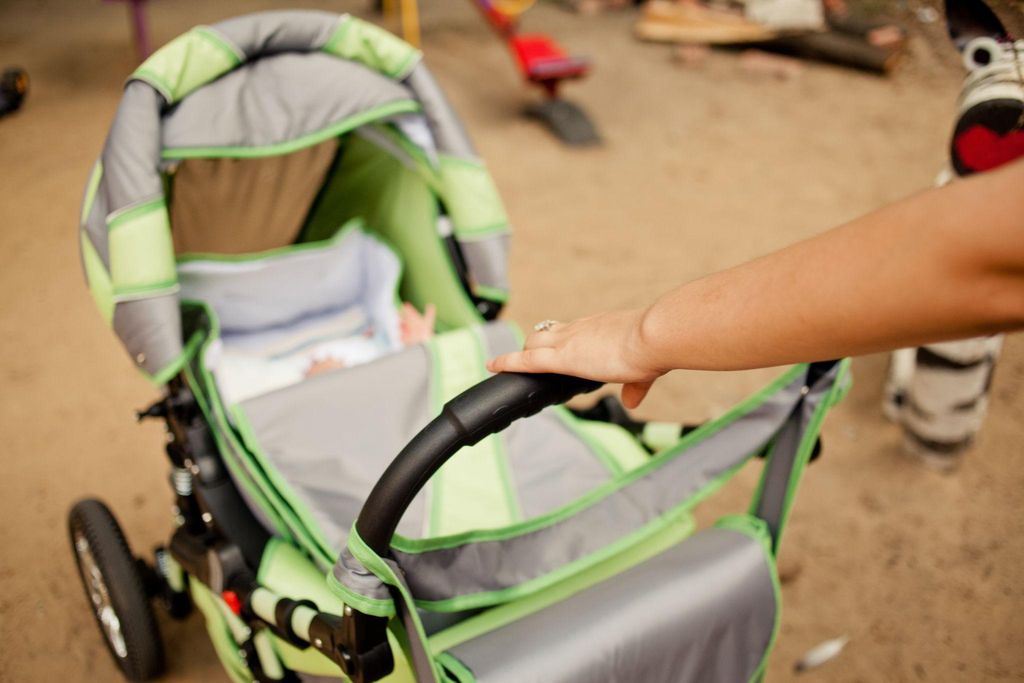 Inspecting second-hand baby gear for safety, with a pram, car seat, and cot.