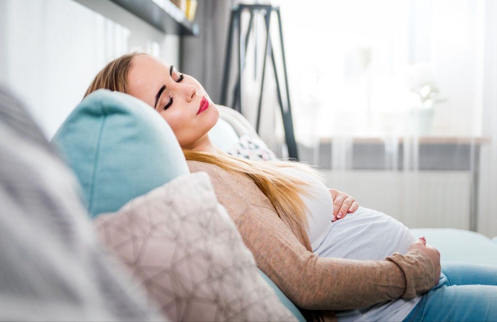 Pregnant woman takes a nap on the couch. Rest and proper sleep are key to avoiding antenatal depression.