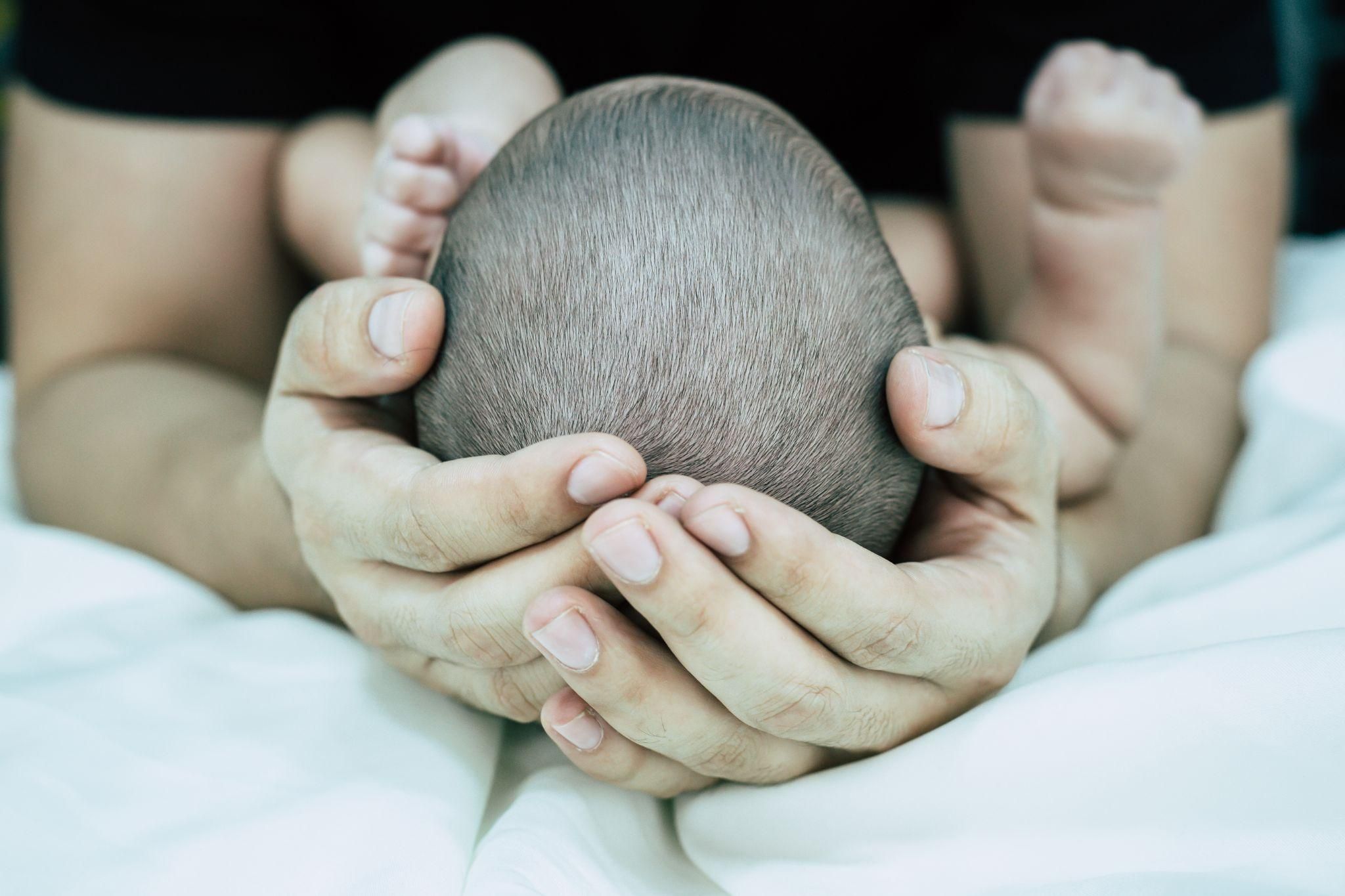 Paediatrician measuring the head circumference of a newborn to assess microcephaly.