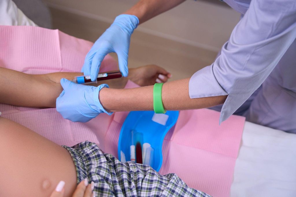 Midwife takes blood sample from pregnant woman for antenatal screening tests at booking appointment.