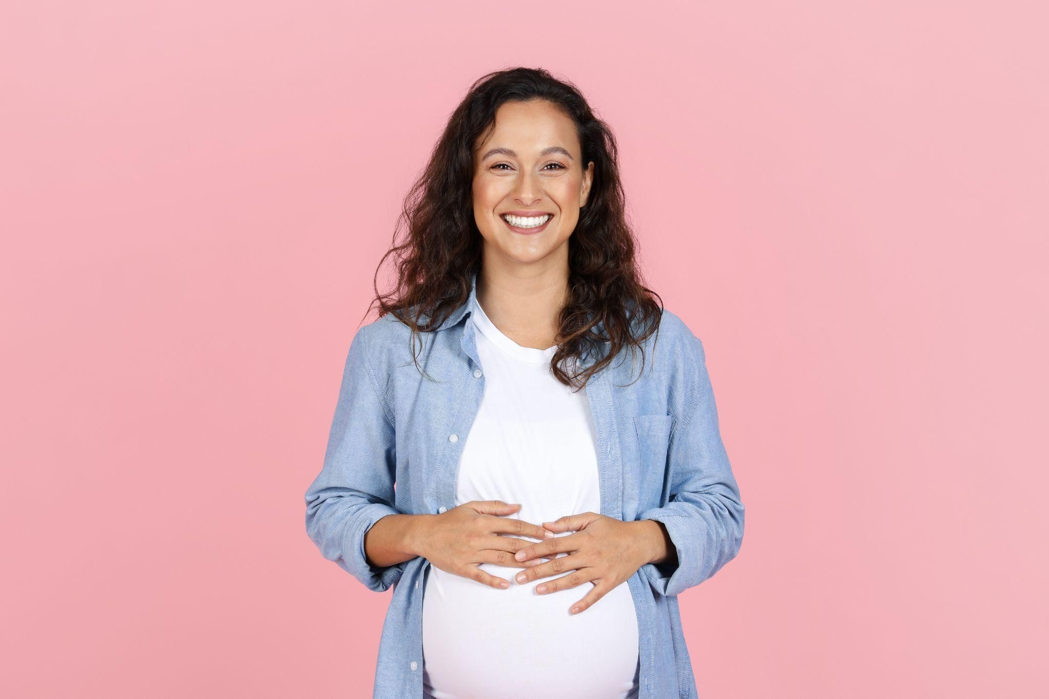 Pregnant woman smiling, celebrating the development of her baby’s limbs and overall growth.