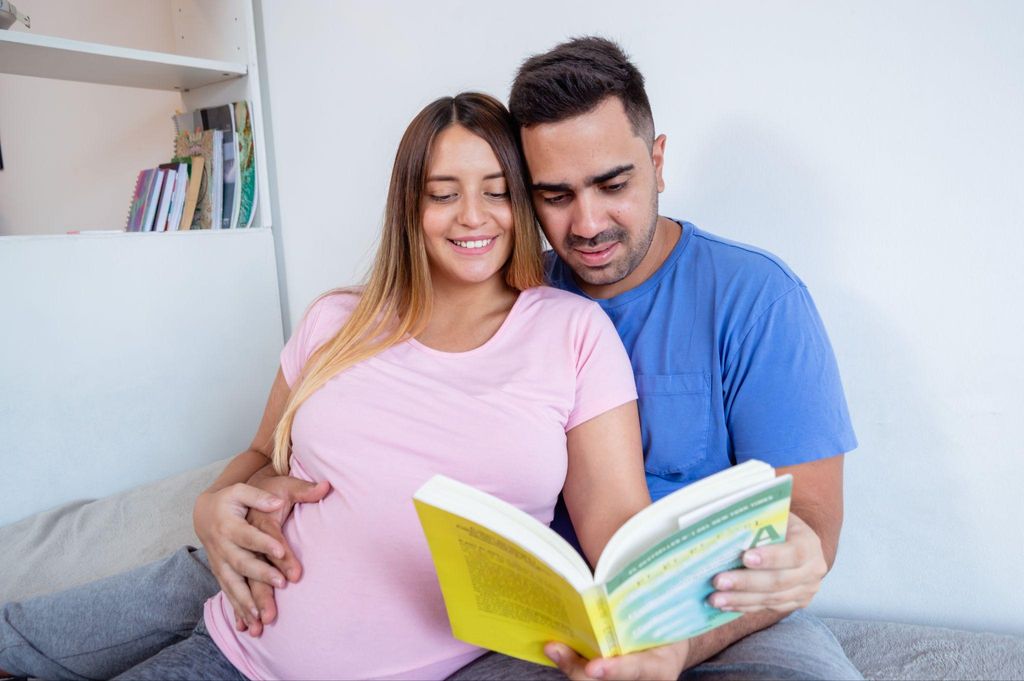 "Expectant dad reading a pregnancy guidebook with a smile."