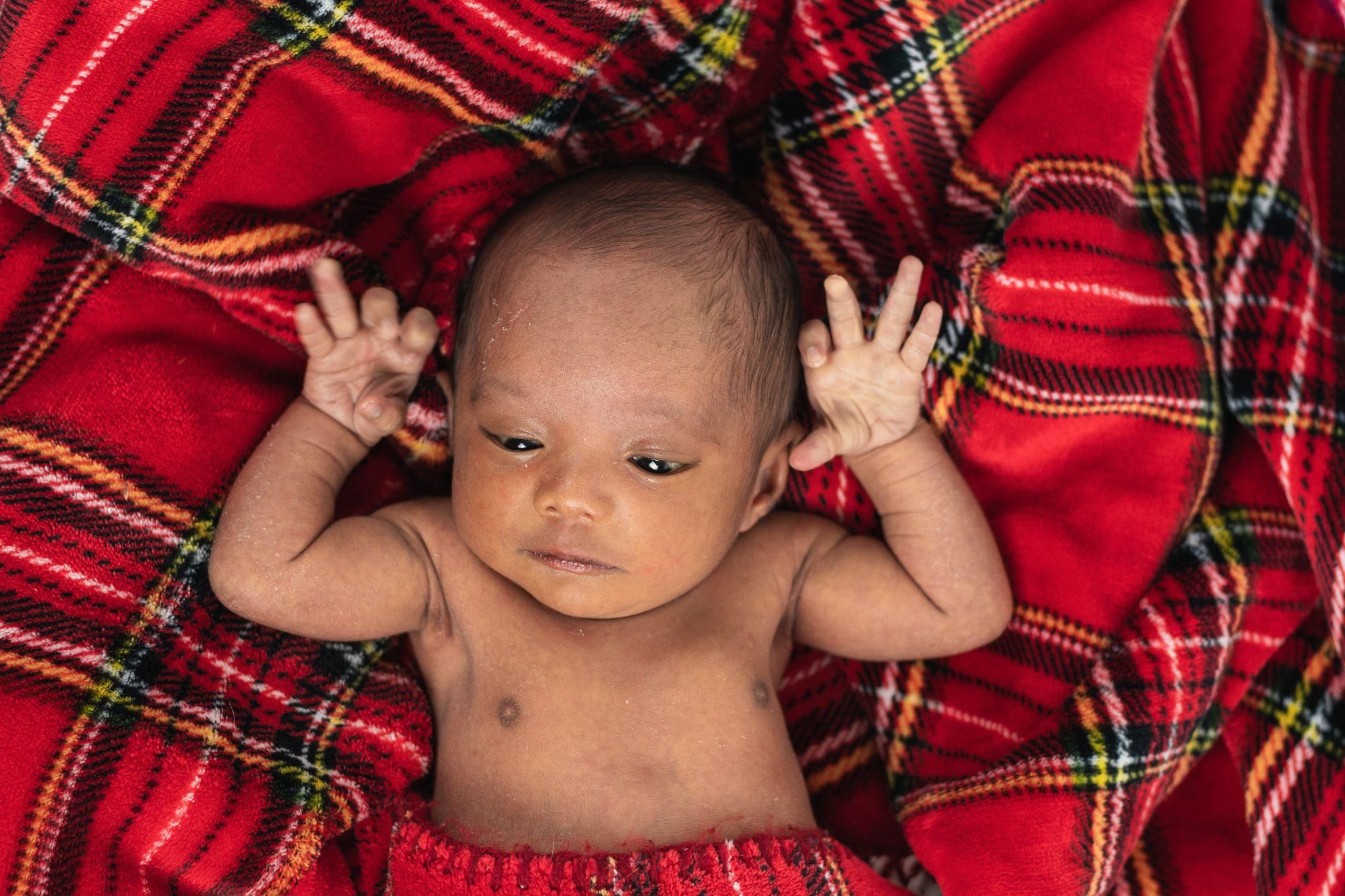 A smiling baby lying on a tummy time mat with toys around.