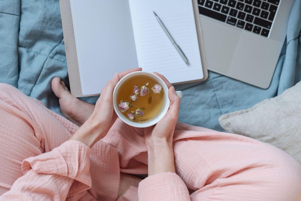 Expectant mother writing in a pregnancy journal, reflecting on her journey with a cup of tea and ultrasound photos.