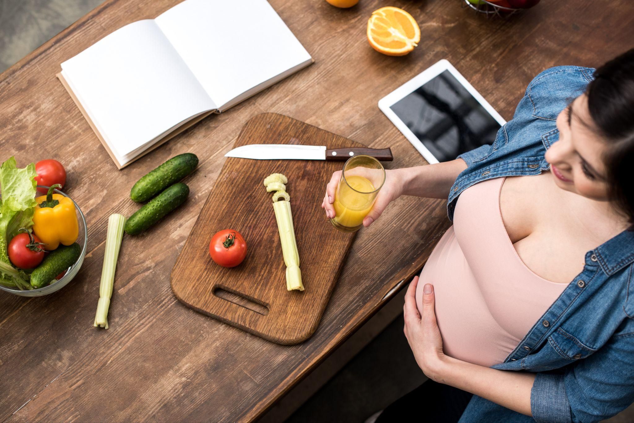 "Pregnancy meal planning book surrounded by healthy ingredients."