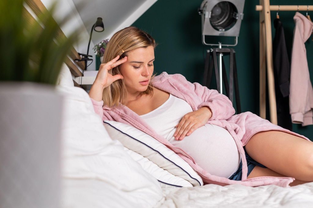 A mother-to-be looking out at nature, deep in thought about life after having a baby.