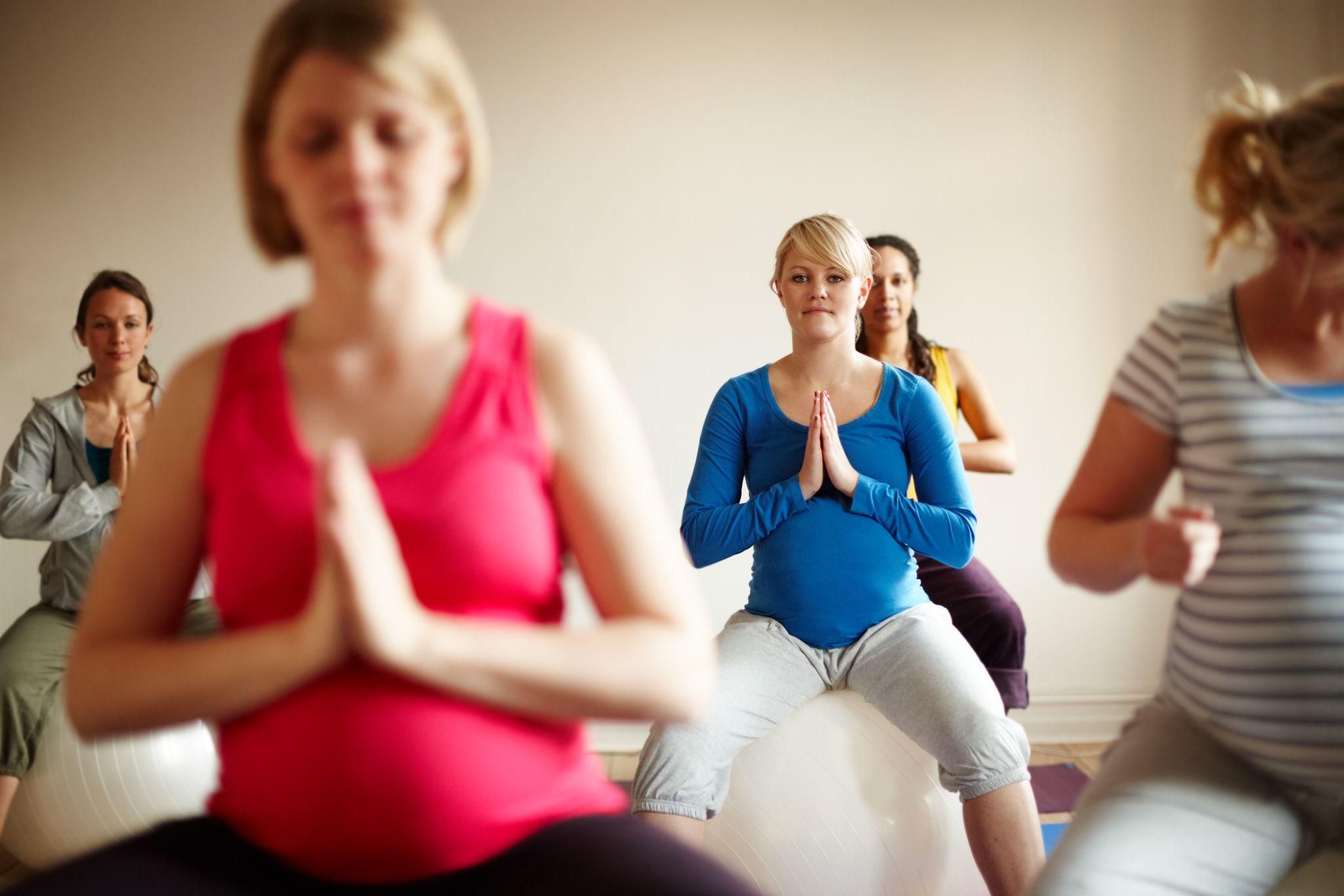 Pregnant woman attending antenatal class with partner and midwife.