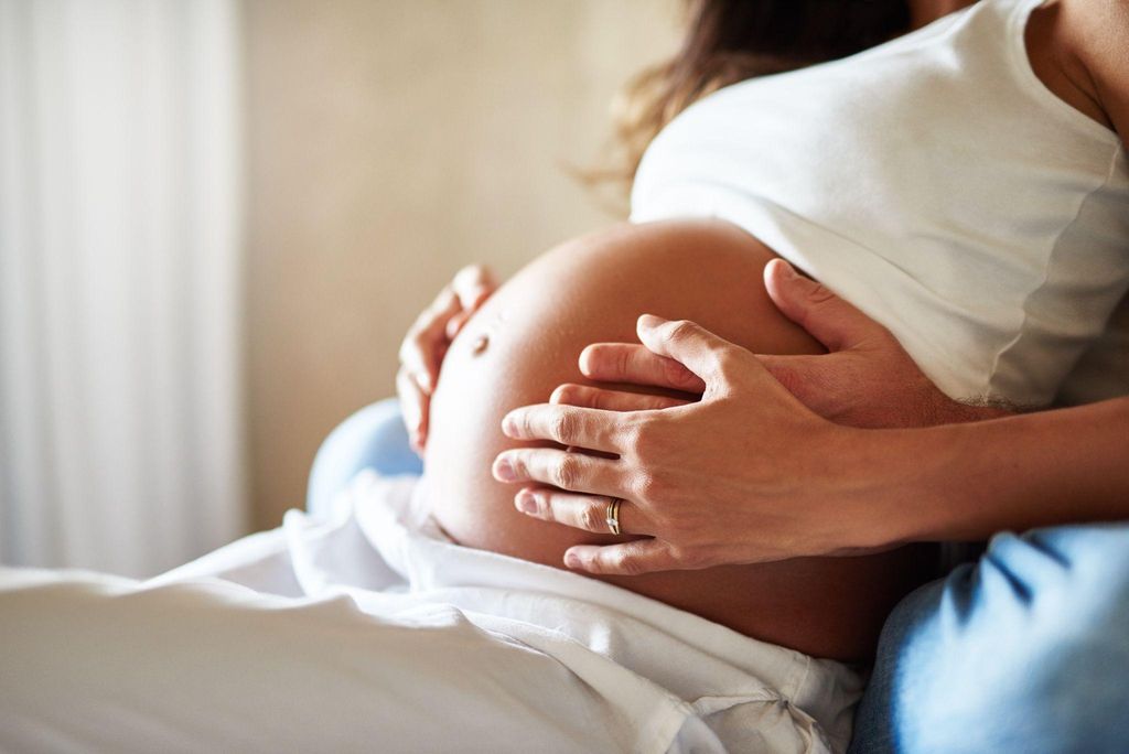 Expectant mother smiling as she bonds with her unborn baby, feeling gentle movements.