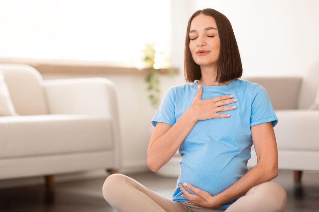 Pregnant woman practising breathing exercises to manage fear of labour, part of an antenatal care routine.