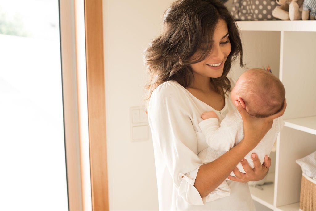 New mum holds newborn and supports its head in the postnatal period.