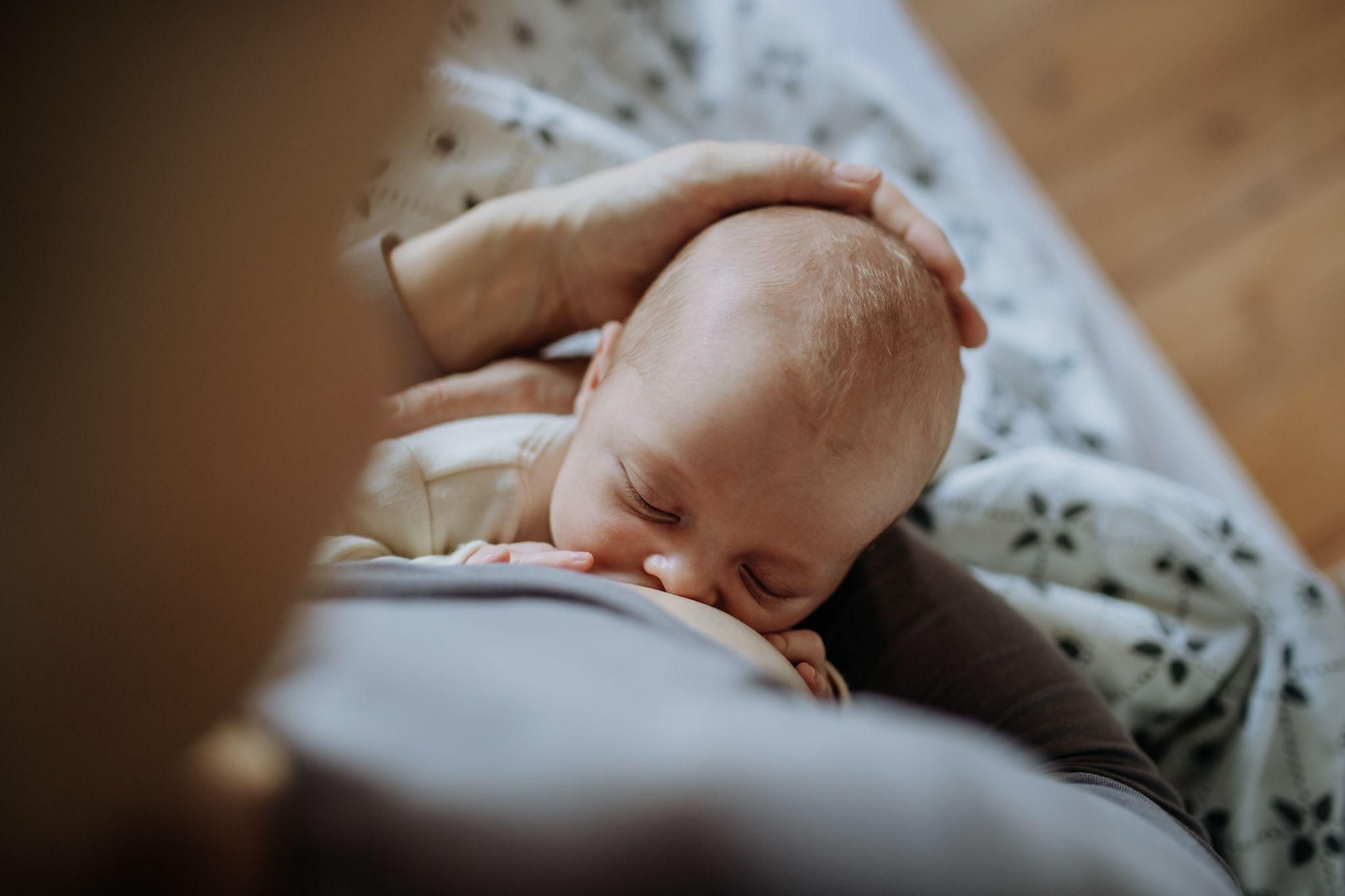 A healthcare professional providing breastfeeding support to a new mother in a hospital.