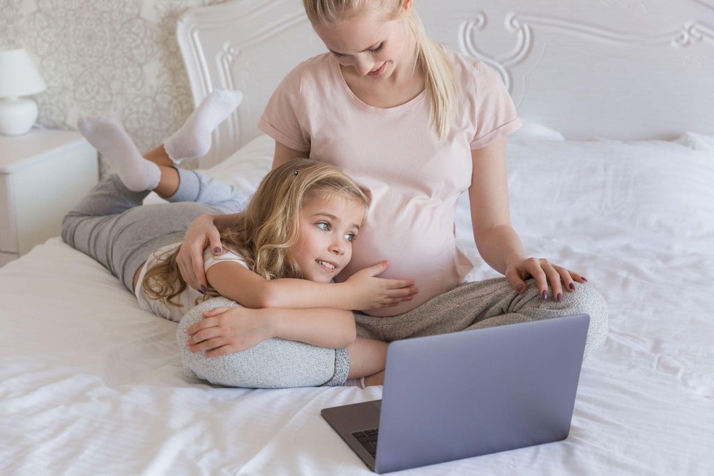 A pregnant woman smiling as she tracks her weight gain using an online tool.